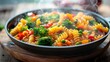 A top view of a steaming bowl of pasta colorful vegetables like broccoli, peas, carrots, and bell peppers tossed with al dente pasta in a light and flavorful sauce.