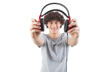 Young handsome smiling man, holding headphones in his hand and showing them to the camera before putting them on to listen to music or play video games, isolated against a white background