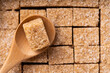 Sugar cubes. Cane sugar cubes background. Brown cane sugar cube in a wooden spoon close up.
