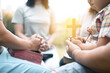 Group of Christian believers clasped hands in prayer, In the church, expressing their faith through worship and reverence for God, symbolized by the cross. Group christian pray concept.