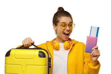 Young excited girl ready for travelling, holding passport with airplane tickets and yellow suitcase for trip, screaming and laughing with joy