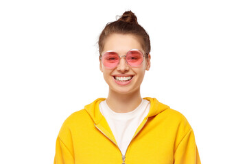 Portrait of young happy teenage girl wearing yellow hoodie and pink glasses, feeling relaxed and smiling happily