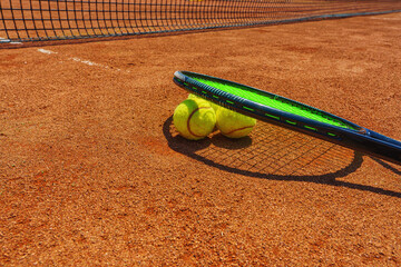 Wall Mural -  A yellow tennis ball and tennis racket lies on the clay court.