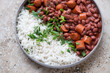 Plate of red beans with sausage and white rice, horizontal shot on a beige granite background, middle close-up