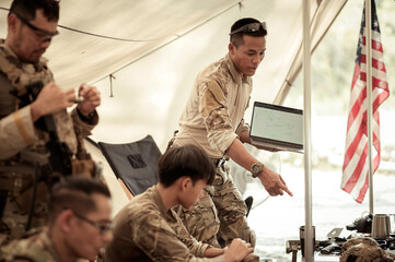 Wall Mural - Soldiers in camouflage uniforms planning on operation in the camp, soldiers training in a military operation