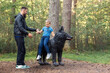 A father helps his son get off a wooden black wolf sculpture on a forest path