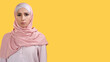 Female portrait. Serious face. Confident strict angry dissatisfied woman in hijab frowning isolated on yellow empty space background.