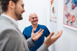 Handsome male patient standing and talking with good looking male doctor in a modern clinic for diagnosis and treatment of eye and sight diseases. Healthcare and medical concept.