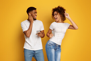 Wall Mural - Black man and woman in earphones listening to music on cell phones