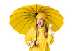 Young girl with rainproof coat and umbrella over isolated chroma key background celebrating a victory in winner position