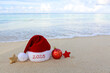 New Year 2025 background with Christmas hat and decorations on Caribbean sand.