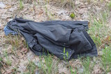 Fototapeta Desenie - one black winter fabric jacket lies on the ground and green grass on the street