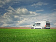 white camper bus in green field under blue sky and clouds in spring day with copy space