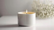 Burning candle on a white table with white flowers in the background