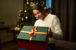 Young woman opening and looking in gift box during Christmas or New Year