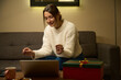 Young attractive woman watching laptop on sofa at table during Christmas