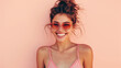 Stylish happy smiling young woman in sunglasses posing on pink studio background