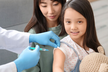 Canvas Print - Little Asian girl with her mother receiving vaccine in clinic