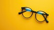 Pair of eyeglasses with black frames on yellow background