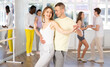 © JackF - Positive woman and man dancing bachata in pair during group dance classin dancing studio