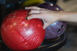 A woman's hand takes a red bowling ball, close-up photo.
