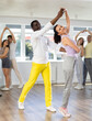 Woman paired with African American man practices movements of Latin tango dance and trains to perform movements during lesson in choreography studio.