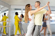 Happy young caucasian man and woman dancing paired latin dance in modern ballroom