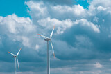 Fototapeta Lawenda - Windmills set on a cloudy sky background.Natural renewable clean eco energy. Alternative energy sources.Environmentally friendly natural energy source. 