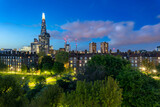 Fototapeta Uliczki - A residental neighbourhood with a geen park and illuminated buildings including skyscrapper Shard in London during blue hour