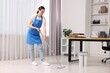 © New Africa - Cleaning service. Woman washing floor with mop in office