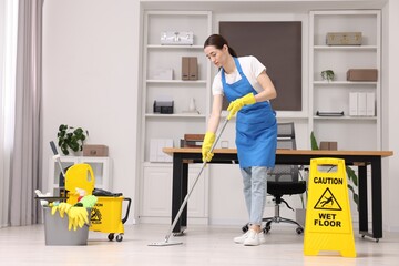 Canvas Print - Cleaning service worker washing floor with mop. Bucket with supplies and wet floor sign in office