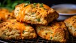 Savory scones with cheddar and chives, close-up, highlighting the golden crust and flaky layers, on a wire cooling rack. 