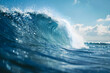Close up of a wave in the ocean with a blue sky and sunlight shining on the water's surface.