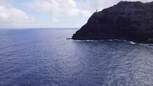 Drone Footage Approaching Makapu'u Point Lighthouse On Top Of A Steep Cliff Overlooking The Blue Pacific Ocean Water With White Capped Waves Crashing Onto The Rocky Shore Below Oahu Hawaii