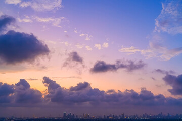 Wall Mural - Yellow orange violet purple gradient with cumulus clouds over the city