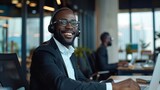 Fototapeta  - Cheerful black man wearing a headset at a modern office exudes friendliness and professionalism