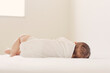 © amanaimages - ベッドで眠る赤ちゃんの背中