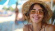© Dionysus - A smiling young woman wearing a straw hat and sunglasses at the beach on a sunny day.