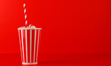 Fototapeta Tulipany - Paper cup with cola and ice over red background