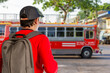 Sustainable transport, Sustainable tourism reduces global warming and saves money, traveling by bus, Asian male tourist holding a travel backpack, waiting for a bus at the station
