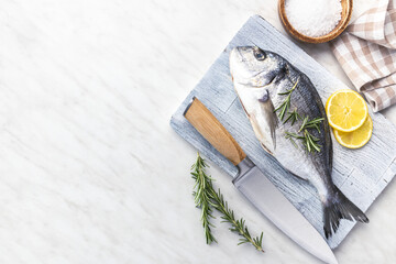 Wall Mural - Fresh sea bream fish on cutting board on kitchen table. Top view.