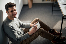 Smiling Businessman Sitting With Tablet PC And Digitized Pen In Office