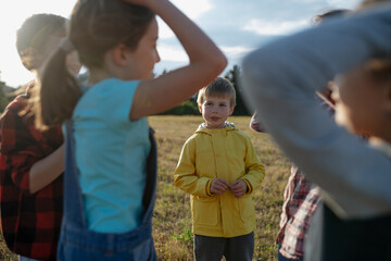 Poster - Portrait of young classmate playing hand clapping game outdoors. Students during field teaching class, standing in the middle of meadow, having fun.