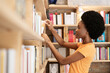 © Westend61 - Afro woman choosing books from store
