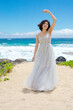 Teen girl in white dress twirling on Hawaiian beach
