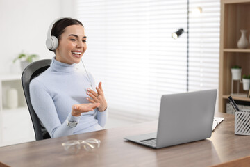 Poster - Young woman in headphones using video chat during webinar at table in office