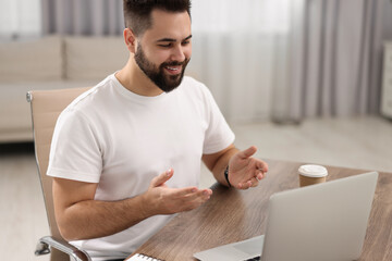 Poster - Young man using video chat during webinar at table in room