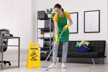 Poster - Cleaning service worker washing floor with mop. Bucket with supplies and wet floor sign in office