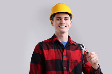 Poster - Young man holding pliers on grey background