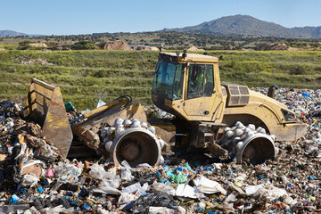 Wall Mural - Heavy machinery shredding garbage in an open air landfill. Pollution